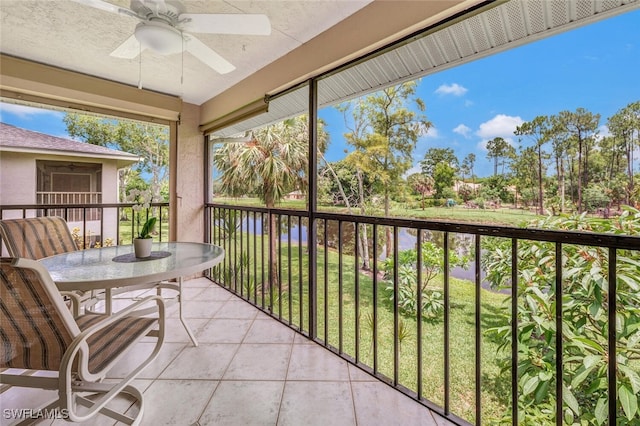 sunroom / solarium with ceiling fan and a water view