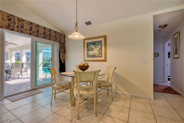 dining space with light tile patterned flooring and vaulted ceiling