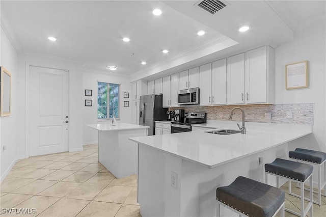 kitchen featuring a center island, kitchen peninsula, sink, appliances with stainless steel finishes, and a kitchen breakfast bar