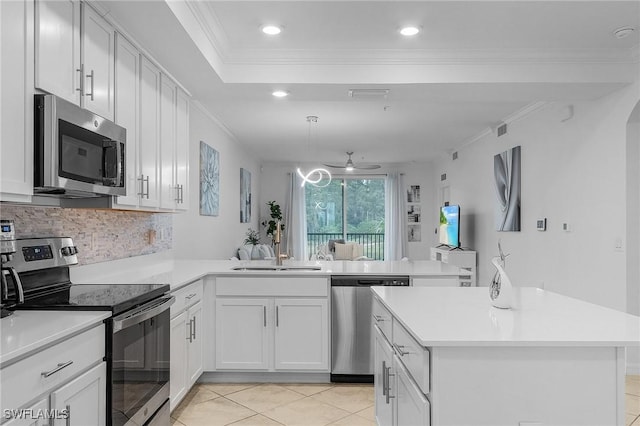 kitchen with a peninsula, ornamental molding, stainless steel appliances, and a sink