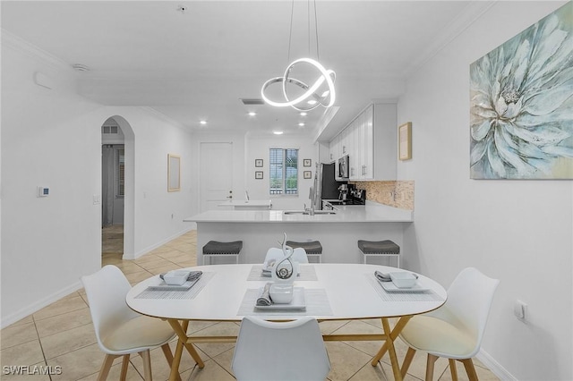 dining room featuring arched walkways, light tile patterned floors, visible vents, ornamental molding, and baseboards