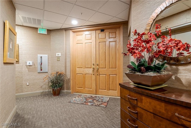 foyer entrance featuring a drop ceiling and dark colored carpet