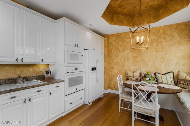 kitchen featuring decorative light fixtures, light hardwood / wood-style flooring, white cabinetry, and white appliances