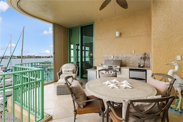 balcony featuring area for grilling, ceiling fan, a grill, and a water view