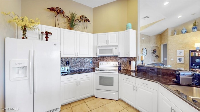 kitchen with white appliances, light tile patterned flooring, a sink, and white cabinetry