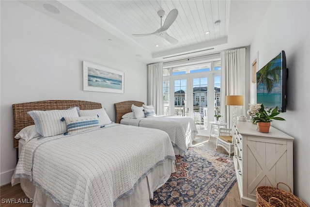 bedroom with wood ceiling, ceiling fan, hardwood / wood-style floors, and a tray ceiling