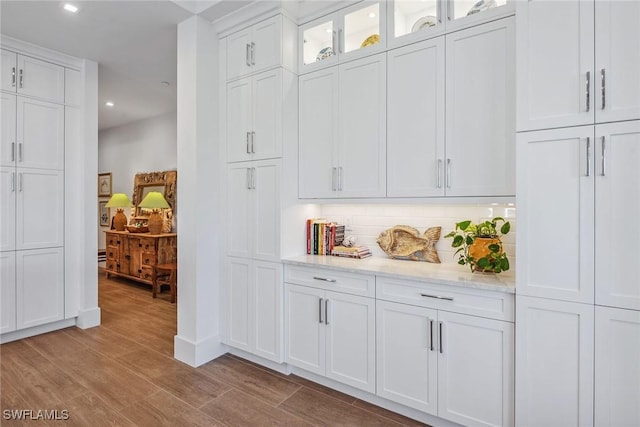 bar with light stone countertops, white cabinets, and tasteful backsplash