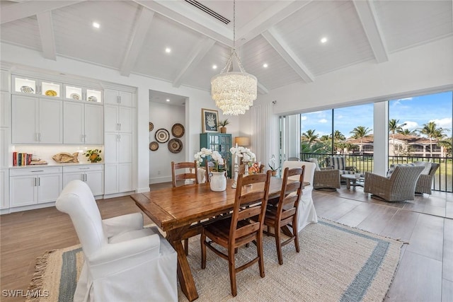 dining room featuring light wood-type flooring, a notable chandelier, and vaulted ceiling with beams