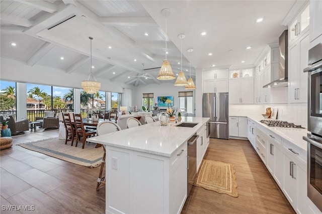 kitchen with pendant lighting, wall chimney exhaust hood, a kitchen island, a kitchen bar, and stainless steel appliances