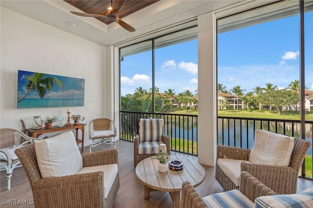 sunroom with ceiling fan and a water view