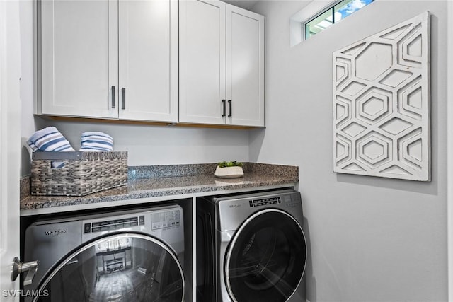 clothes washing area featuring washer and dryer and cabinets