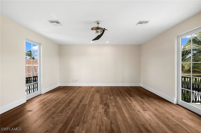 empty room featuring ceiling fan, dark hardwood / wood-style flooring, and a healthy amount of sunlight