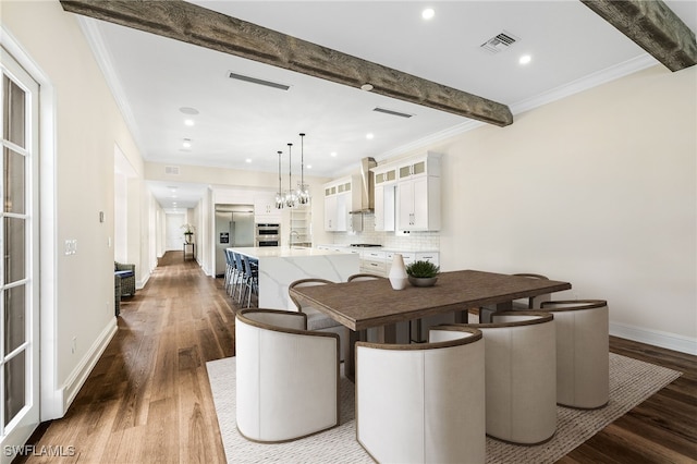 dining space with hardwood / wood-style flooring, sink, ornamental molding, and beam ceiling