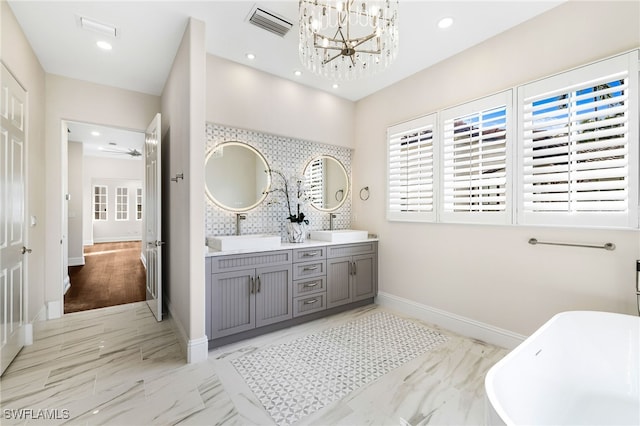 bathroom with a washtub, a notable chandelier, and vanity