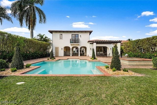 rear view of house featuring a pergola, a patio, a pool with hot tub, a balcony, and a yard