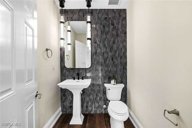 bathroom with hardwood / wood-style flooring, sink, tile walls, and toilet