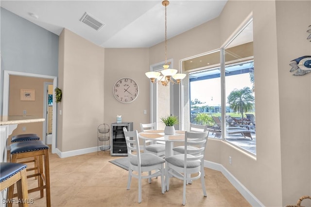 tiled dining space with a notable chandelier, a towering ceiling, and beverage cooler