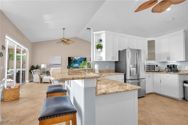 kitchen with a kitchen breakfast bar, stainless steel refrigerator with ice dispenser, light stone counters, white cabinets, and kitchen peninsula