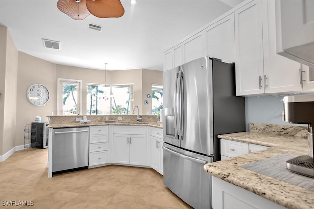 kitchen with sink, white cabinetry, decorative light fixtures, stainless steel appliances, and light stone countertops