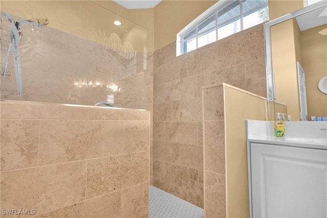 bathroom with a tile shower and vanity