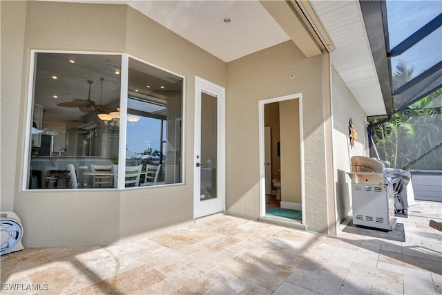 view of patio with a lanai, area for grilling, and ceiling fan