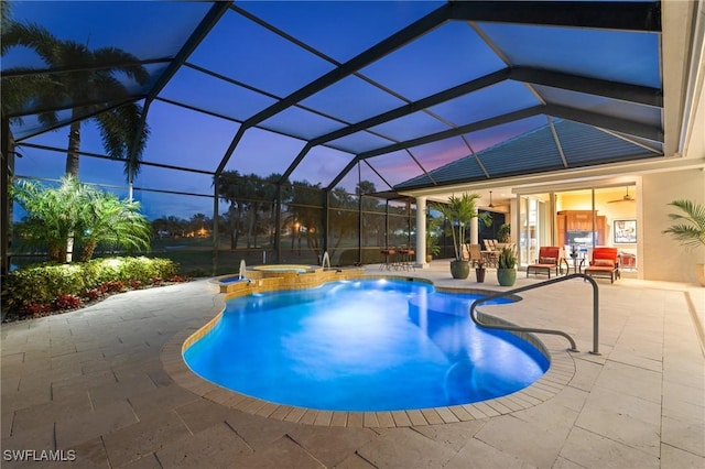 pool at dusk featuring an in ground hot tub, ceiling fan, a patio area, and glass enclosure