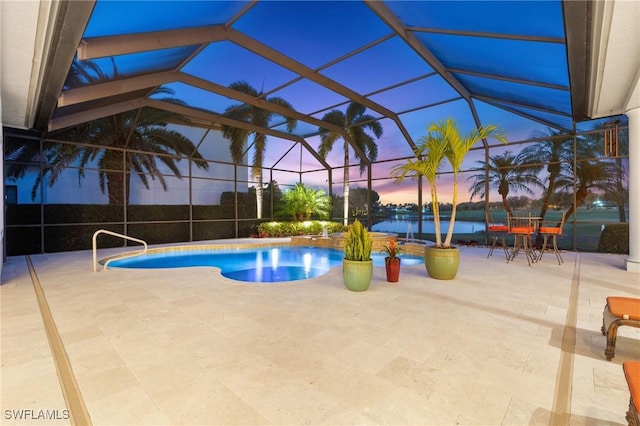 pool at dusk featuring a water view, a lanai, and a patio area