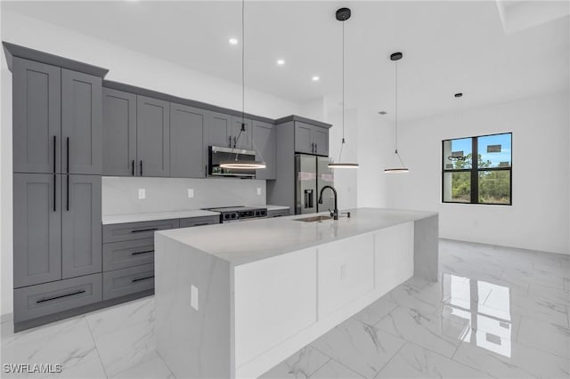 kitchen with pendant lighting, appliances with stainless steel finishes, an island with sink, sink, and gray cabinetry