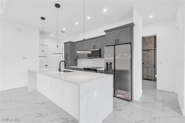 kitchen featuring decorative light fixtures, a kitchen island with sink, appliances with stainless steel finishes, and sink