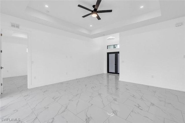 empty room with a raised ceiling and ceiling fan