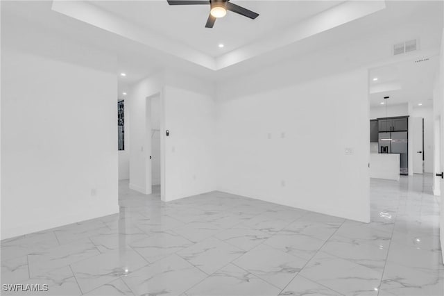 unfurnished room featuring ceiling fan and a raised ceiling