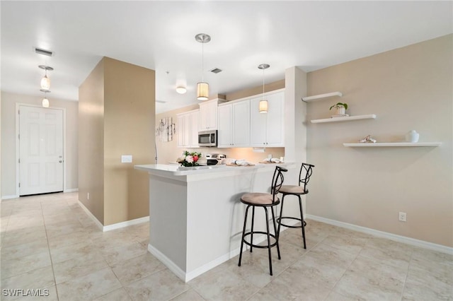 kitchen with a kitchen bar, decorative light fixtures, kitchen peninsula, stainless steel appliances, and white cabinets