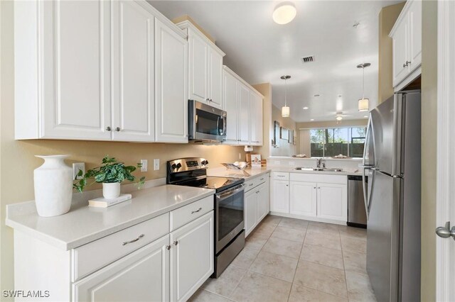 kitchen featuring sink, light tile patterned floors, pendant lighting, stainless steel appliances, and white cabinets