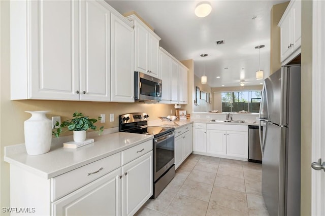 kitchen with sink, decorative light fixtures, light tile patterned floors, appliances with stainless steel finishes, and white cabinets