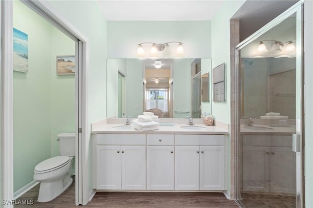 bathroom with vanity, toilet, a shower with door, and wood-type flooring