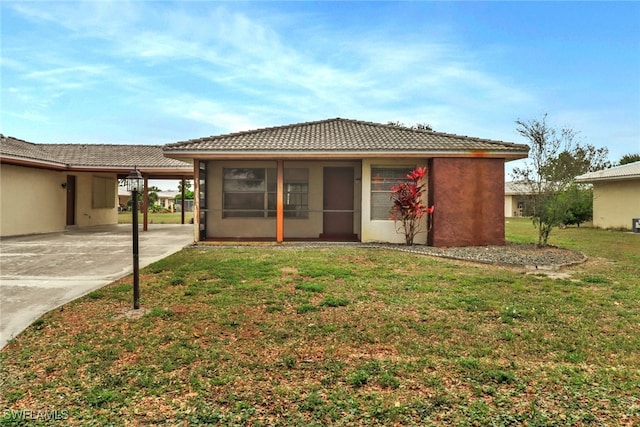 view of front of house with a sunroom, a front yard, and a carport