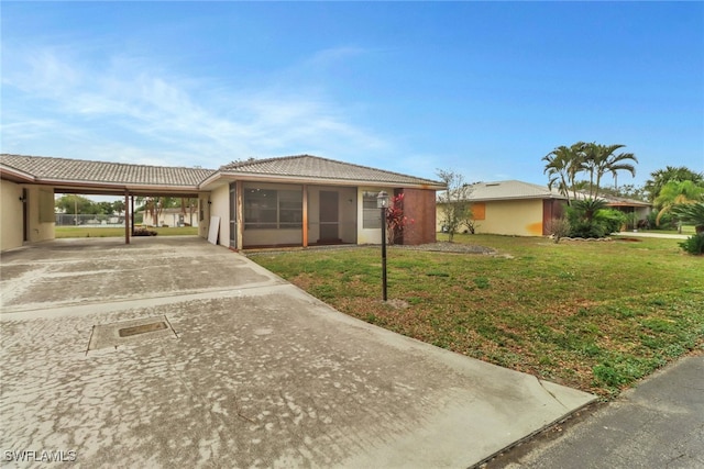 single story home with a front yard, a sunroom, and a carport