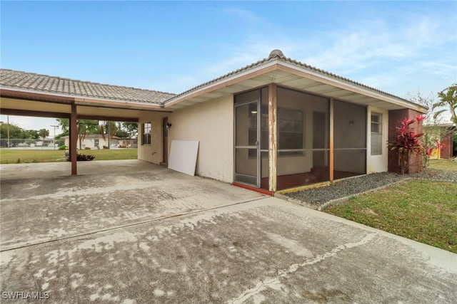 view of property exterior featuring a sunroom and a carport