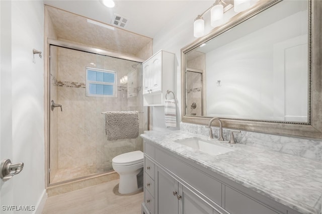 bathroom with vanity, toilet, and a shower with door