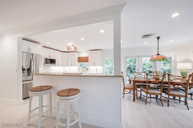 kitchen featuring white cabinetry, light stone counters, stainless steel fridge with ice dispenser, hanging light fixtures, and backsplash