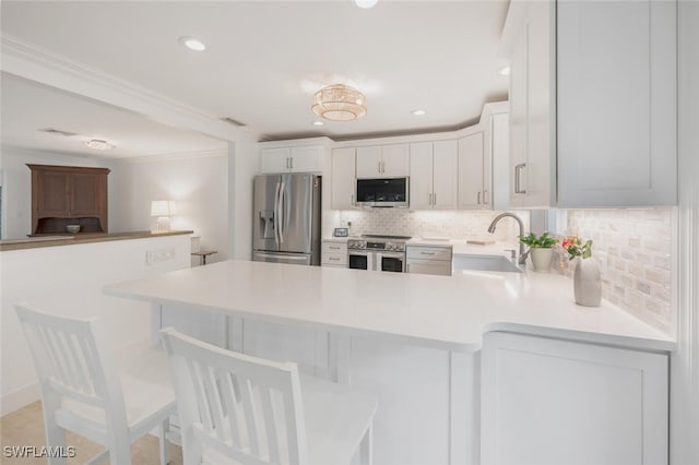 kitchen with appliances with stainless steel finishes, a breakfast bar, white cabinetry, sink, and kitchen peninsula