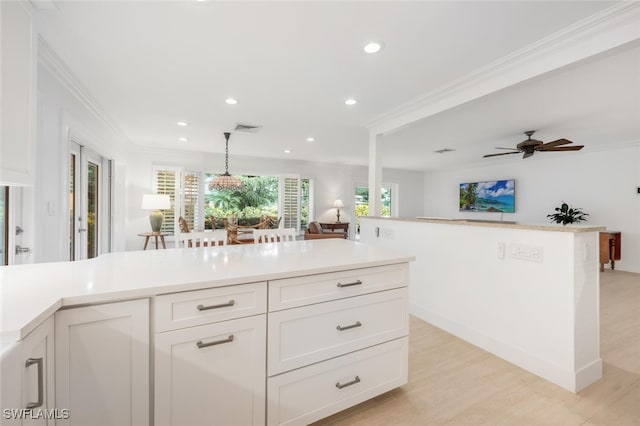 kitchen with ornamental molding, decorative light fixtures, light hardwood / wood-style flooring, and white cabinets