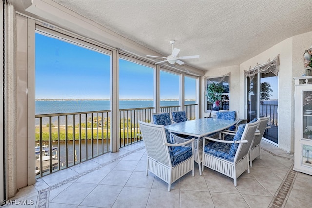 sunroom / solarium featuring a water view and ceiling fan