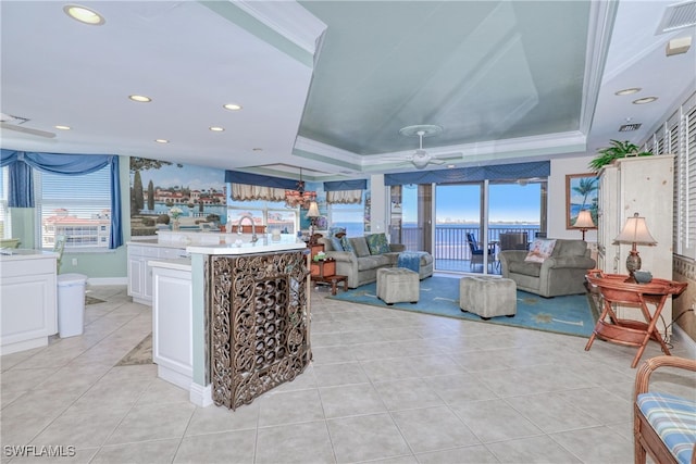 living room featuring a tray ceiling, a wealth of natural light, sink, and light tile patterned floors