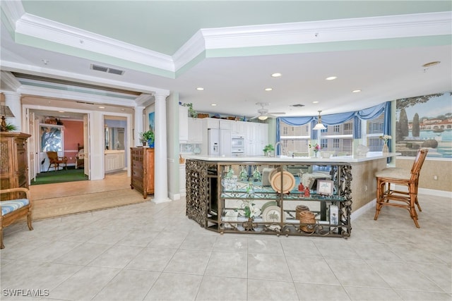 kitchen featuring light tile patterned floors, ornamental molding, white cabinets, and ornate columns