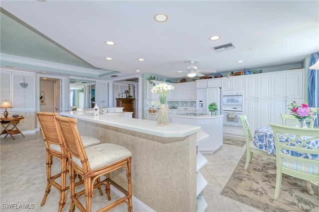 kitchen with a spacious island, white cabinetry, paneled built in fridge, and light tile patterned floors