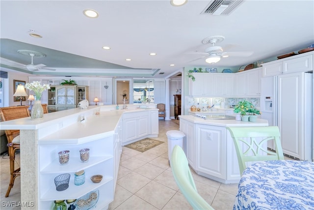 kitchen with a large island with sink, white cabinetry, and white refrigerator with ice dispenser