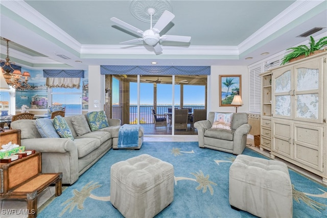 carpeted living room with crown molding, a raised ceiling, and ceiling fan