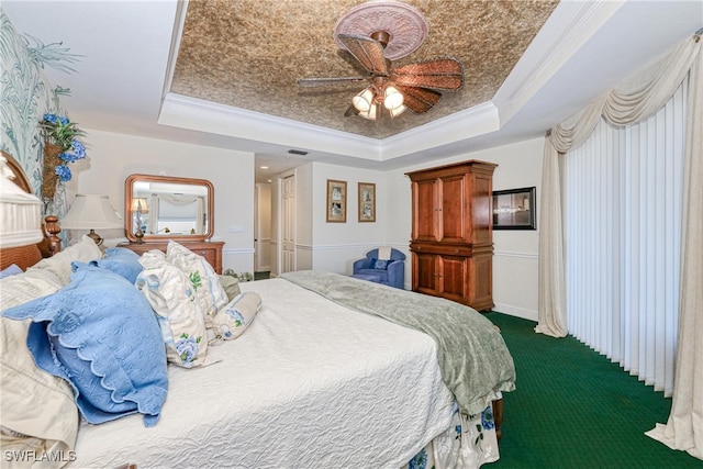 carpeted bedroom with a tray ceiling, ornamental molding, and ceiling fan