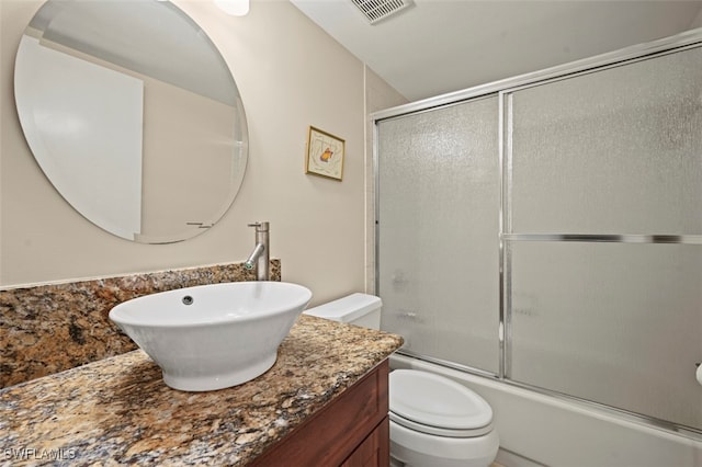 full bathroom featuring enclosed tub / shower combo, vanity, and toilet